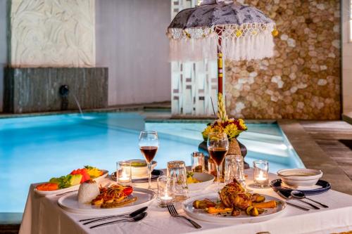a table with food and wine and a swimming pool at Vivara Bali Private Pool Villas & Spa Retreat in Jimbaran