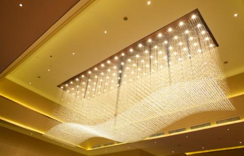 a large glass chandelier hanging from a ceiling at Astara Hotel Balikpapan in Balikpapan