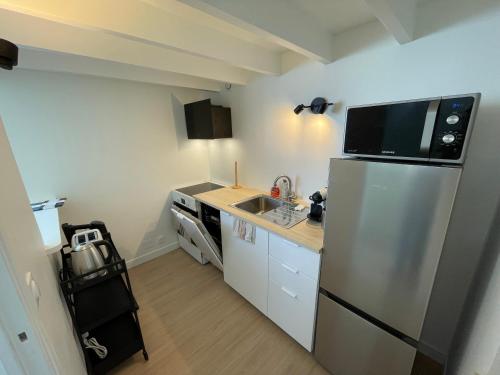 une cuisine avec un réfrigérateur en acier inoxydable et un évier dans l'établissement Studio entre Paris et Versailles, à Ville-dʼAvray