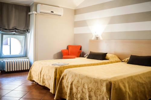 a room with two beds and an orange chair at Lizard Hotel in Como