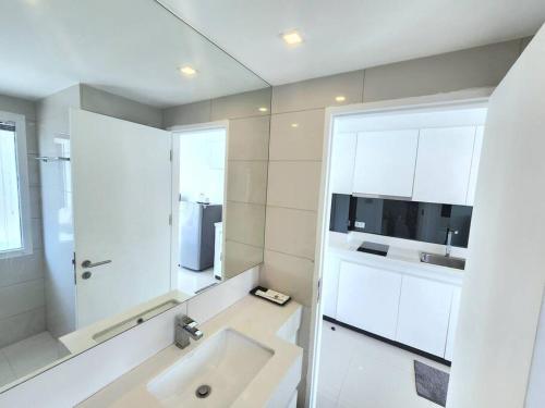 a white bathroom with a sink and a mirror at Nice apartment in Pattaya Central