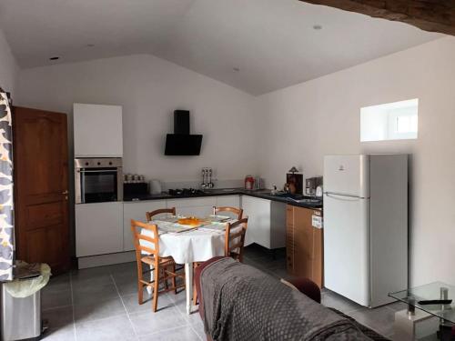 une cuisine avec une table avec des chaises et un réfrigérateur dans l'établissement Chez Mamisa, à Saint-Mandé-sur-Brédoire
