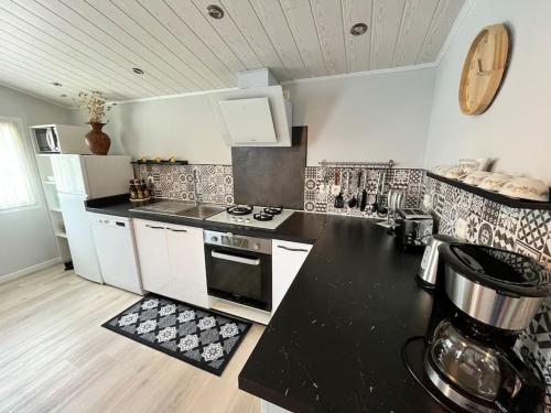 une cuisine avec un comptoir noir et des armoires blanches dans l'établissement Cabane Meysouet-maison refaite à neuf vélo Bourg, à Mimizan