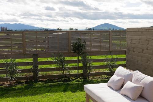 a white couch sitting in front of a fence at Willow View Cottage - Beautiful farm views close to Waitomo in Otorohanga