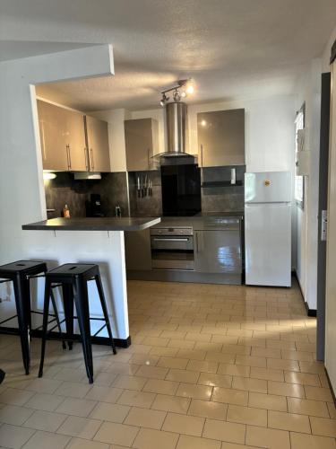 - une cuisine avec des appareils électroménagers blancs et des tabourets noirs dans l'établissement Chez lydia, au Cap d'Agde