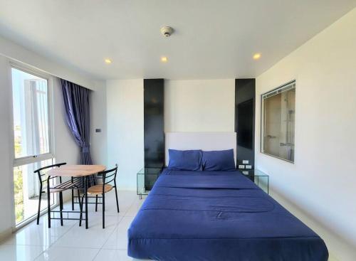 a bedroom with a blue bed and a table at Nice studio comfortable in Pattaya Central