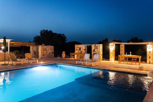 a swimming pool at night with chairs and a table at Masseria della Piana in Villanova di Ostuni