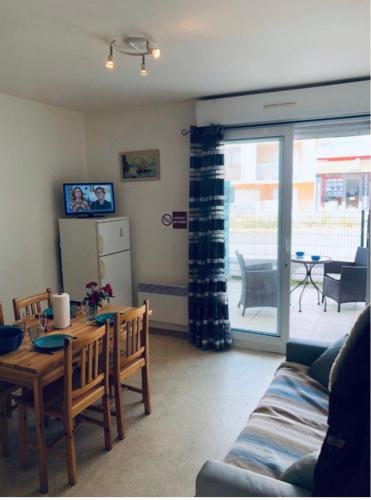 un salon avec une table et un réfrigérateur dans l'établissement Appartement Stella Plage, à Cucq