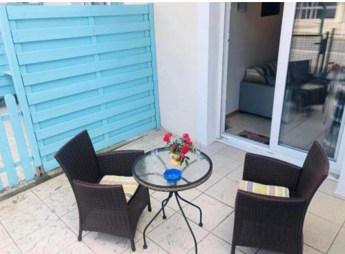 - une table avec des chaises et un vase de fleurs sur la terrasse dans l'établissement Appartement Stella Plage, à Cucq