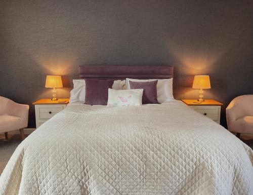 a bedroom with a large white bed with two lamps at Samuel cottage in Caernarfon