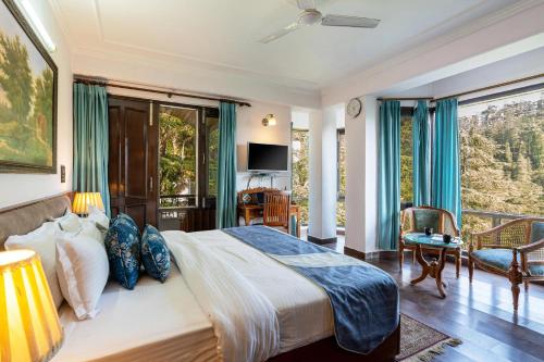 a bedroom with a large bed and a balcony at Simla Manor by VEO - Part of StayVista in Shimla