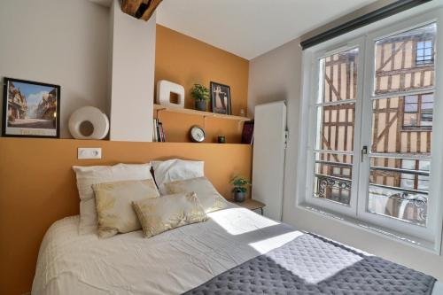 un lit dans une chambre avec une grande fenêtre dans l'établissement Le Petit Vauluisant - Cosy & Confort - Mon Groom, à Troyes