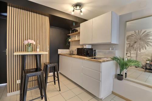 une cuisine avec des armoires blanches et un comptoir avec des tabourets dans l'établissement Le Petit Vauluisant - Cosy & Confort - Mon Groom, à Troyes