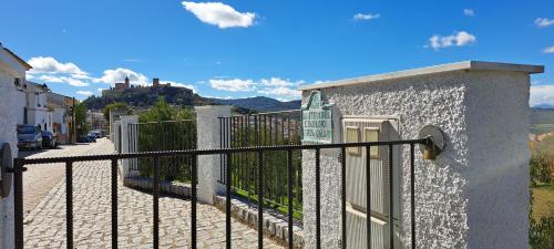 a fence next to a street with a castle in the background at Cauchil Chico in Alcalá la Real