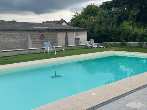 - une grande piscine bleue avec 2 chaises dans la cour dans l'établissement maison d hôte avec piscine, à Lèves