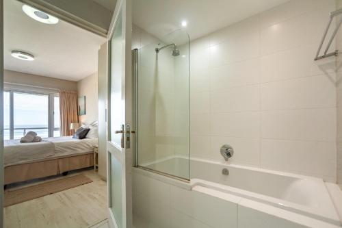 a bathroom with a shower and a bath tub at Luxury Private Beachfront 2 bedroom Dolphin Apartment, Blouberg, Cape Town in Bloubergstrand
