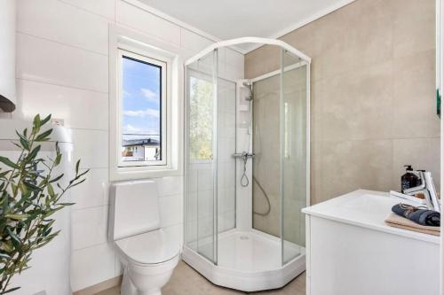 Un baño blanco con ducha y lavabo. en Bo moderne på Falkum med utsikt, en Skien