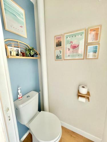 La salle de bains est pourvue de toilettes blanches et de photos murales. dans l'établissement Appart avec Balcon et Place de Parking à Berck-Plage, à Berck-sur-Mer