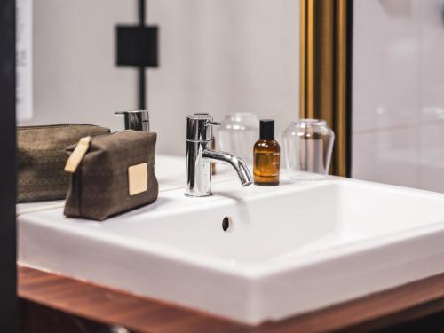 a bathroom sink with a bottle of alcohol and a purse at Billie Hôtel in Nantes