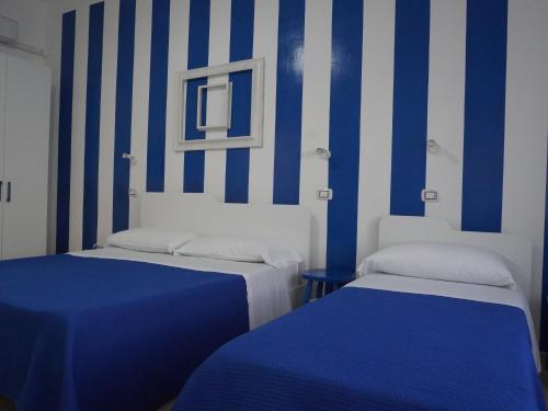 two beds in a room with blue and white stripes at Dimora Terra di Puglia in Torre Santa Sabina