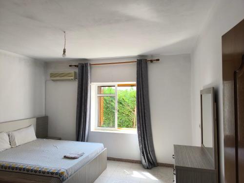 a bedroom with a bed and a window at Green Haven Cottage in Delvinë