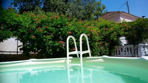 une chaise blanche assise au bord de la piscine dans l'établissement Au nid de mes Anges, à Entrecasteaux