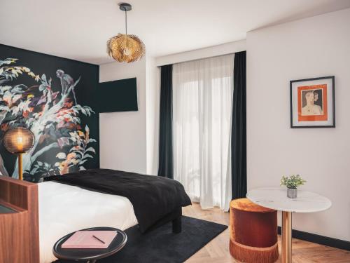 a bedroom with a bed and a table at Billie Hôtel in Nantes