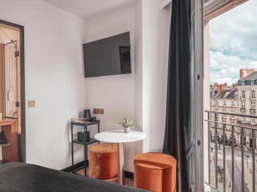 a bedroom with a balcony with a table and a tv at Billie Hôtel in Nantes