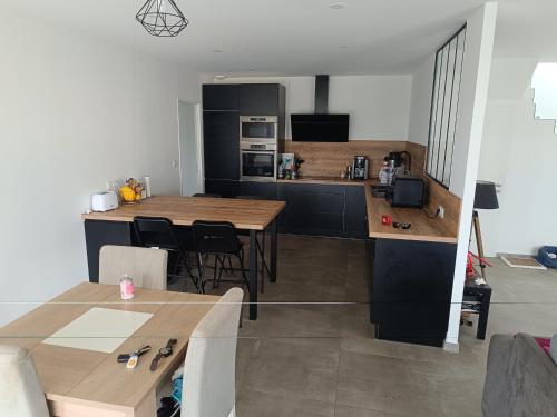 une cuisine avec une table et des chaises et une cuisine avec des armoires noires dans l'établissement Chambre spacieuse #1, à Clonas-sur-Varèze