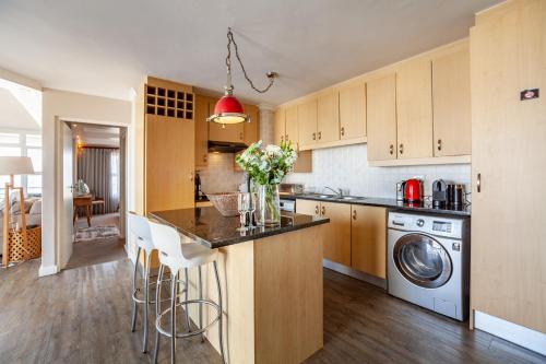 a kitchen with a washer and dryer at Luxury Ocean View Beachfront 2 bed apartment -206 The Waves, Blouberg, Cape Town in Bloubergstrand