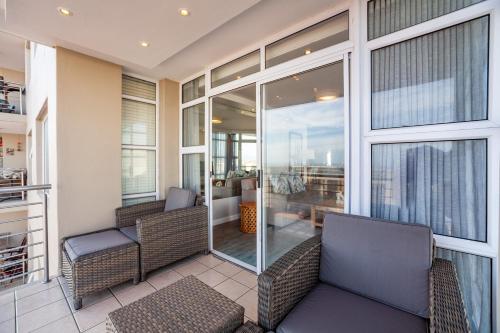 a screened in porch with two chairs and a couch at Luxury Ocean View Beachfront 2 bed apartment -206 The Waves, Blouberg, Cape Town in Bloubergstrand