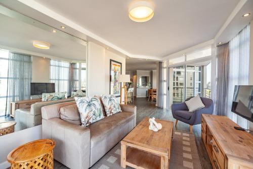 a living room with a couch and a table at Luxury Ocean View Beachfront 2 bed apartment -206 The Waves, Blouberg, Cape Town in Bloubergstrand