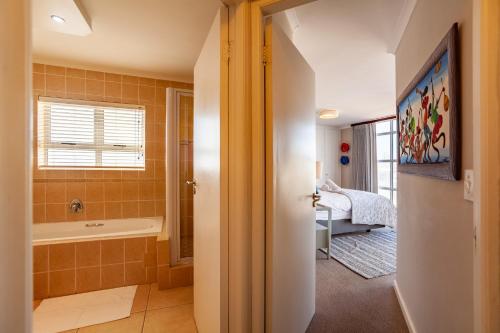 a bathroom with a bath tub and a sink at Luxury Ocean View Beachfront 2 bed apartment -206 The Waves, Blouberg, Cape Town in Bloubergstrand