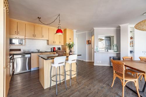 an open kitchen and dining room with a table and chairs at Luxury Ocean View Beachfront 2 bed apartment -206 The Waves, Blouberg, Cape Town in Bloubergstrand