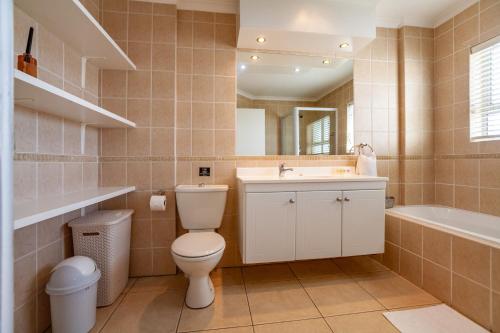 a bathroom with a toilet and a sink and a tub at Luxury Ocean View Beachfront 2 bed apartment -206 The Waves, Blouberg, Cape Town in Bloubergstrand