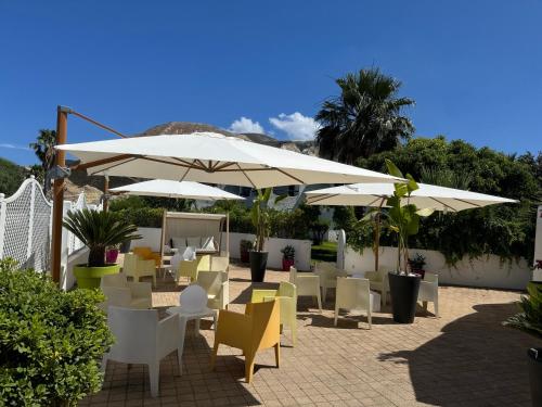 a patio with tables and chairs and umbrellas at Il Caimano B & B, con piscina dall'11 Luglio al 31 Agosto in Vulcano