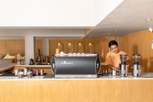 a man standing behind a counter in a kitchen at Horange Phuket Town in Phuket