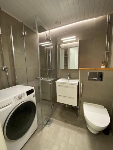 a bathroom with a washing machine and a toilet at City Apartment Sotilaskatu in Iisalmi