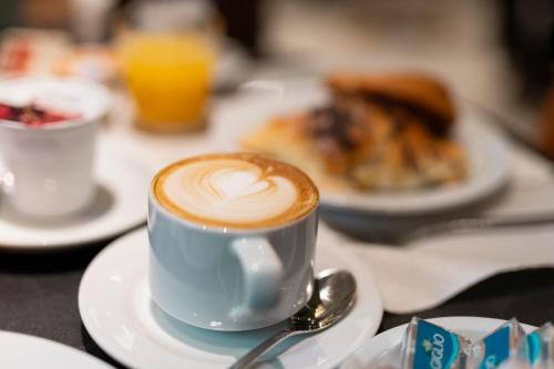 a cup of coffee on a table with plates of food at Hotel Hiberia in Rome
