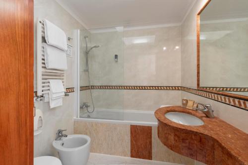 a bathroom with a sink and a tub and a toilet at Hotel Hiberia in Rome