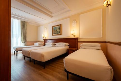 a hotel room with three beds and a window at Hotel Hiberia in Rome