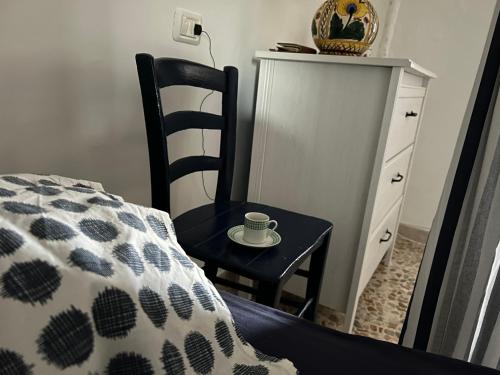 a cup on a table next to a chair next to a bed at Borghetto Sul Mare in Peschici