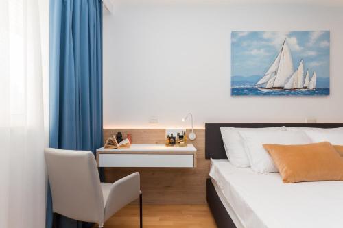 una camera da letto con un letto con una scrivania e un dipinto di una barca a vela di Domus Lauri Garden Palace II a Umag (Umago)