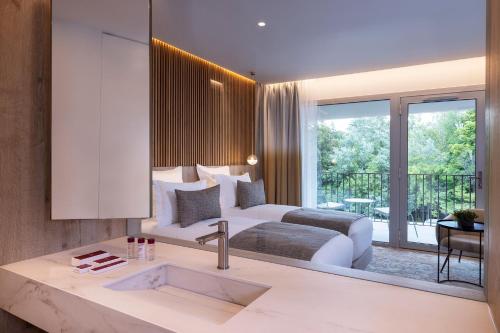 a hotel room with a bed and a bathroom with a sink at Hôtel Spa Restaurant Villa Castellane in Gréoux-les-Bains