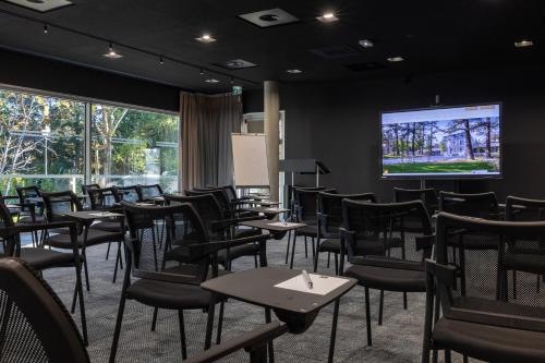 a restaurant with tables and chairs and a projection screen at Hôtel Spa Restaurant Villa Castellane in Gréoux-les-Bains