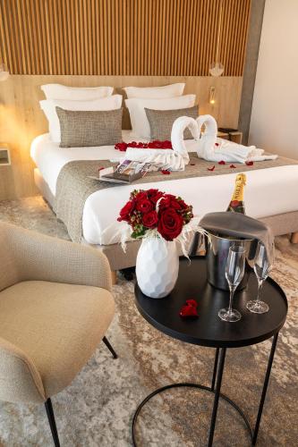 a hotel room with a bed and a table with roses at Hôtel Spa Restaurant Villa Castellane in Gréoux-les-Bains