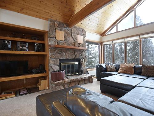 a living room with a couch and a stone fireplace at 61 Jabberwocky Home by Stay Winter Park in Fraser