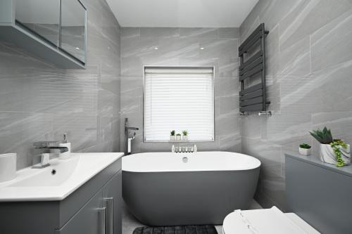 a white bathroom with a tub and a sink at Super Modern 3 bedroom semi-detached. in Rugby