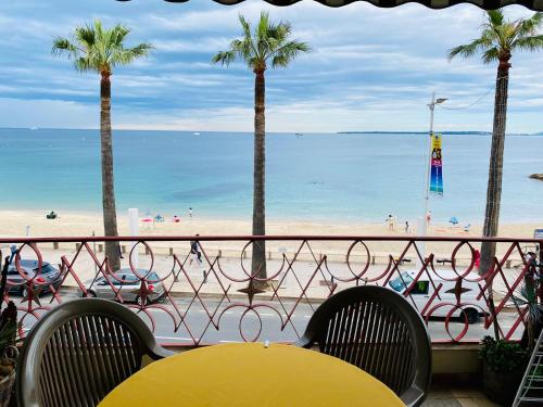 - une vue sur une plage bordée de palmiers, d'une table et de chaises dans l'établissement Constellation, à Juan-les-Pins
