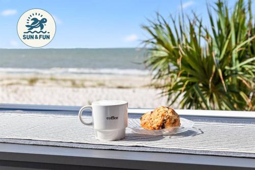 a cup of coffee and a cookie on a plate next to the beach at Sun&Fun - Oceanfront, Quiet beach, Arcade games in Indian Pass